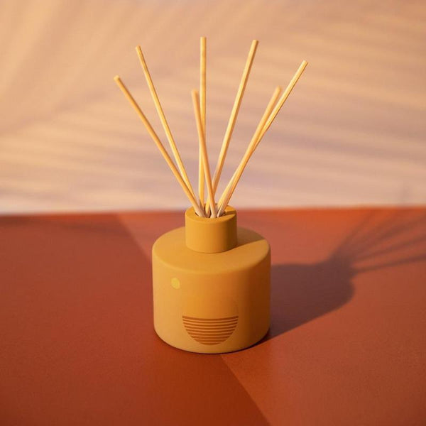 P.F. Candle Co. EU Golden Hour Sunset Reed Diffuser - Product - Custom-printed glass vessels donned with earth-toned motifs, sun shapes, and horizon lines inspired by California scenery.