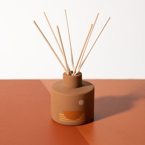 P.F. Candle Co. EU - Swell Sunset 3.75 fl oz Scented Reed Diffuser - Product - Custom-printed glass vessels donned with earth-toned motifs, sun shapes, and horizon lines inspired by California scenery.
